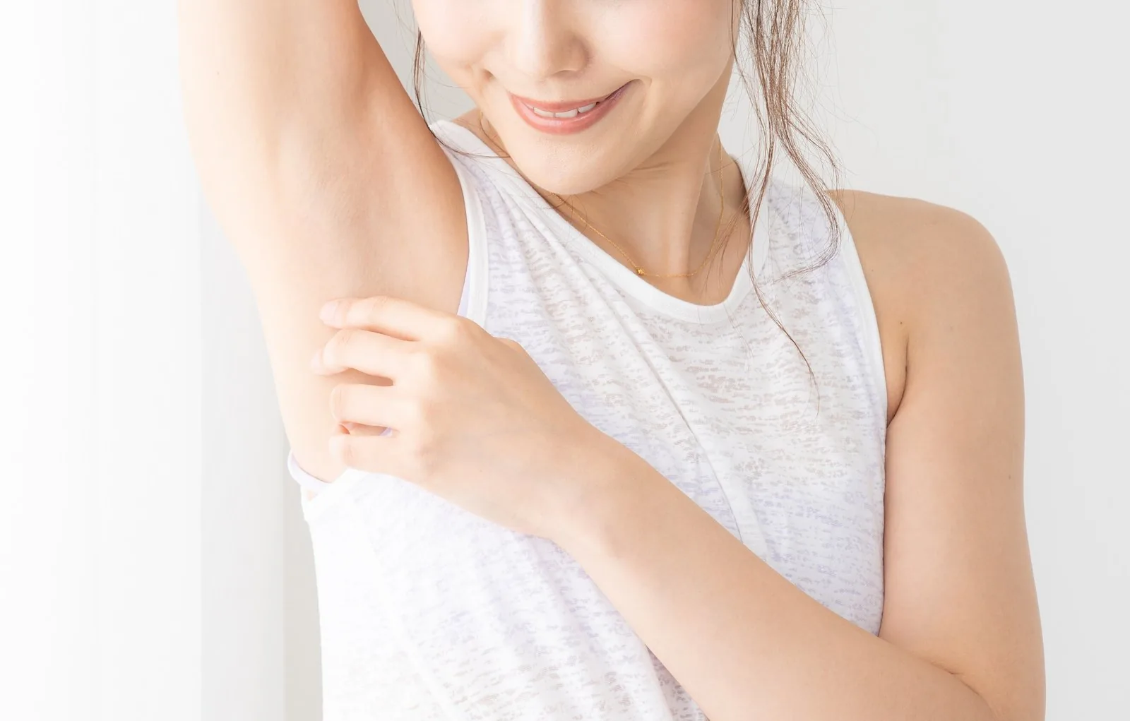 腕を上げてワキに手を添え、ほほえむ女性のモデル写真