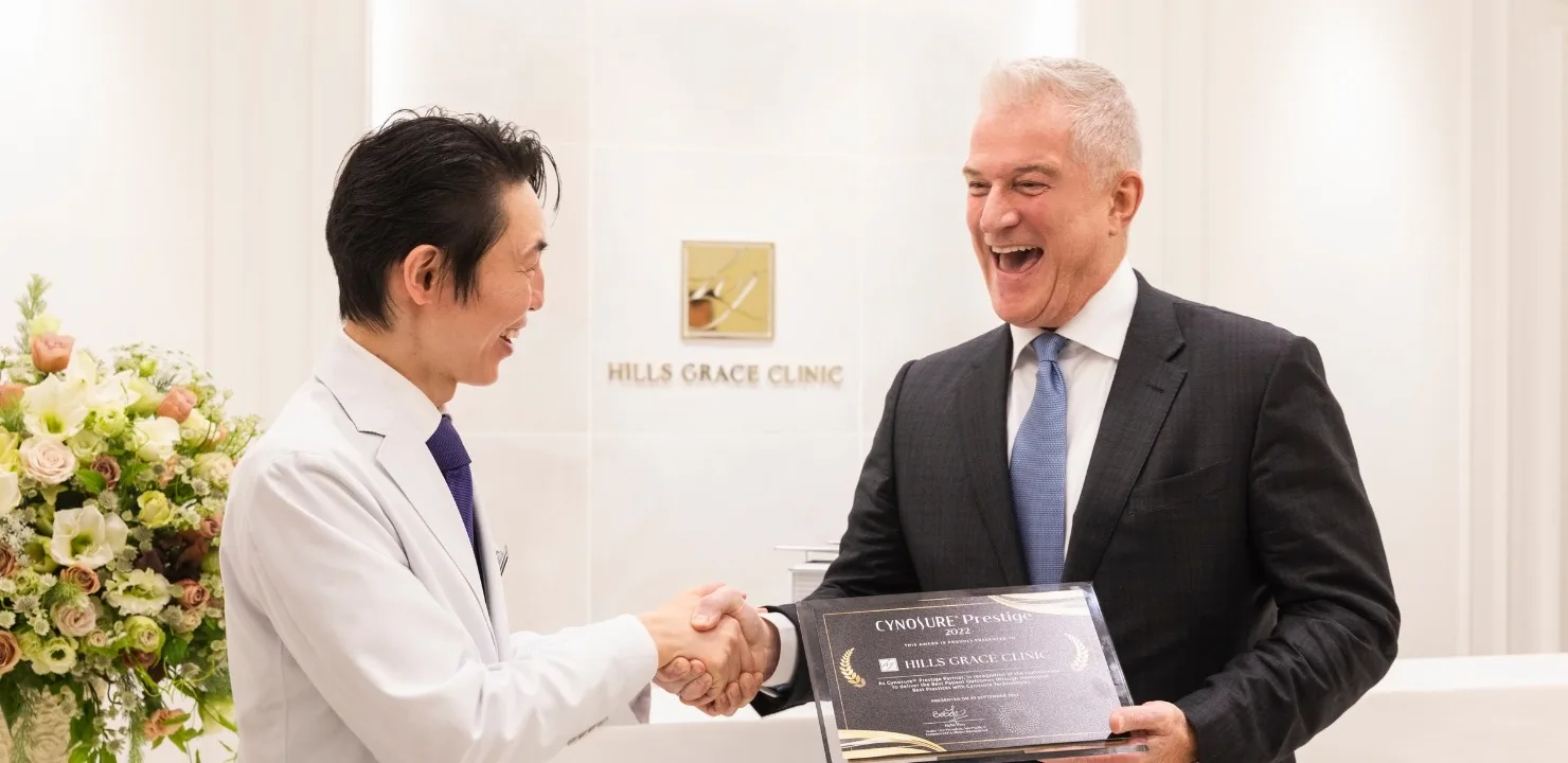 Cynosureのプレステージクリニック認定セレモニーで、認定証を受け取り握手を交わす院長 奥謙太郎