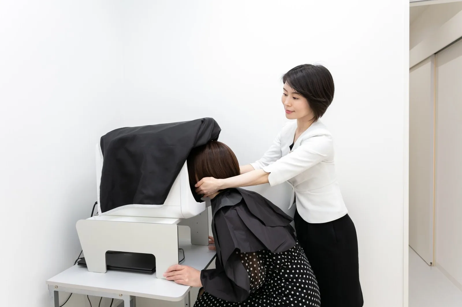 撮影窓に顔を入れた患者さんの頭に手を添えて、位置を合わせているスタッフ