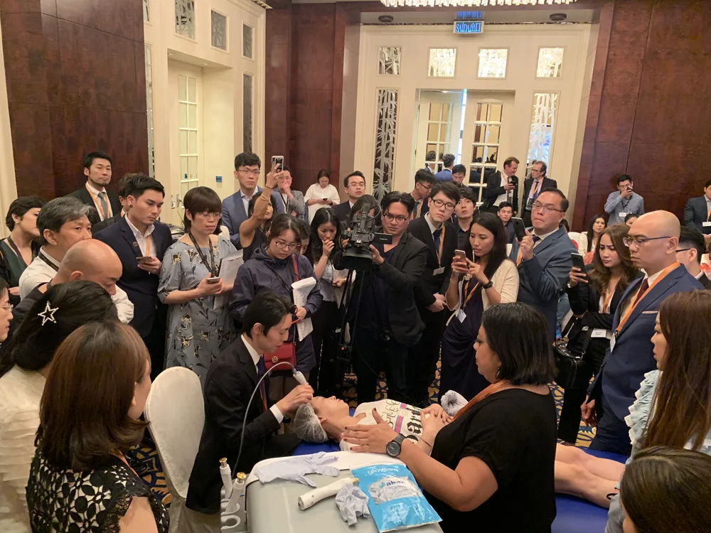 Cynosure APAC Forum 2019の会場で、参加した医師に囲まれ、テンプシュアの照射を実演する院長 奥謙太郎