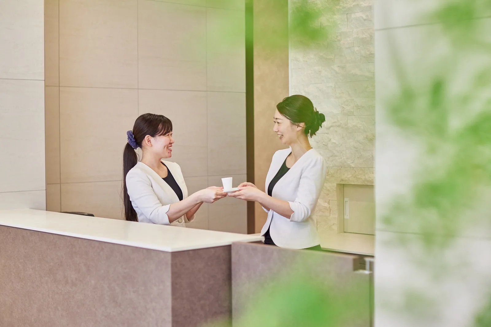受付で、スタッフ同士が笑顔で言葉を交わしている様子