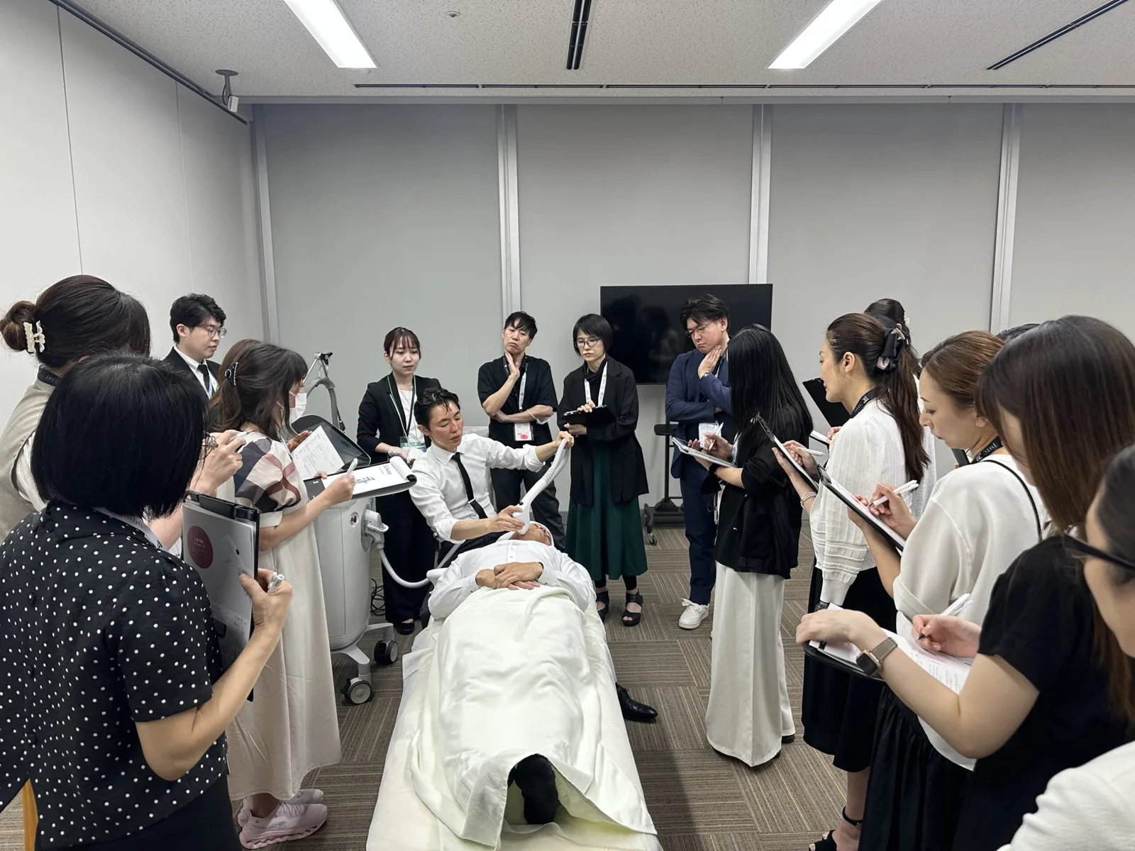 日本美容皮膚科学会で、医師に囲まれてソフウェーブのライブデモンストレーションを行う院長 奥謙太郎